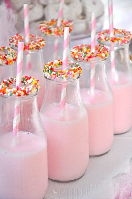 pink milk with sprinkles and straws in small glass bottles on a table