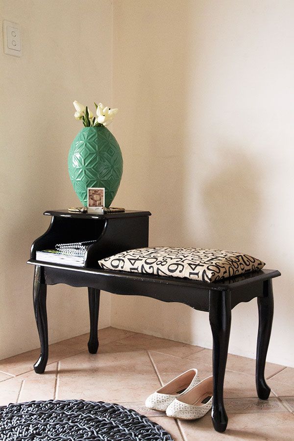 a black table with a green vase on top and a leopard print seat pad next to it