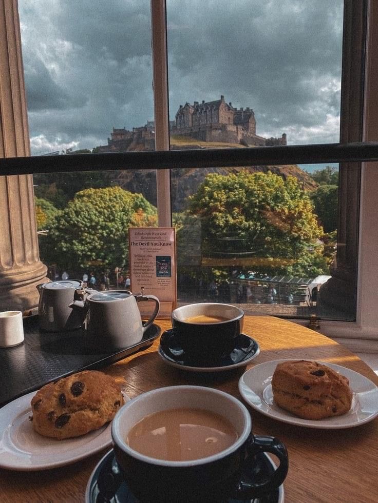 there is a cup of coffee and two cookies on the table next to each other