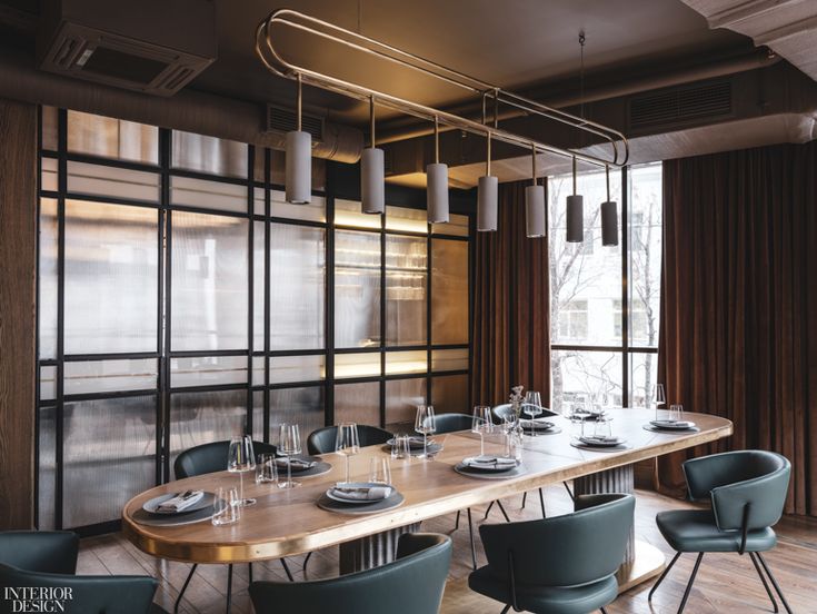 a long table with blue chairs in front of a large window and wooden paneled wall