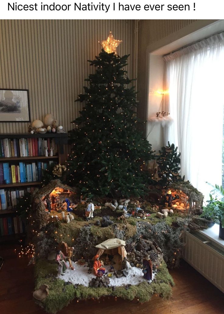 a christmas tree is in the corner of a room with nativity decorations on it