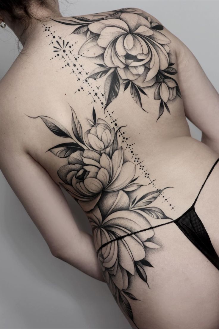 the back of a woman's body with flowers tattooed on her chest and side