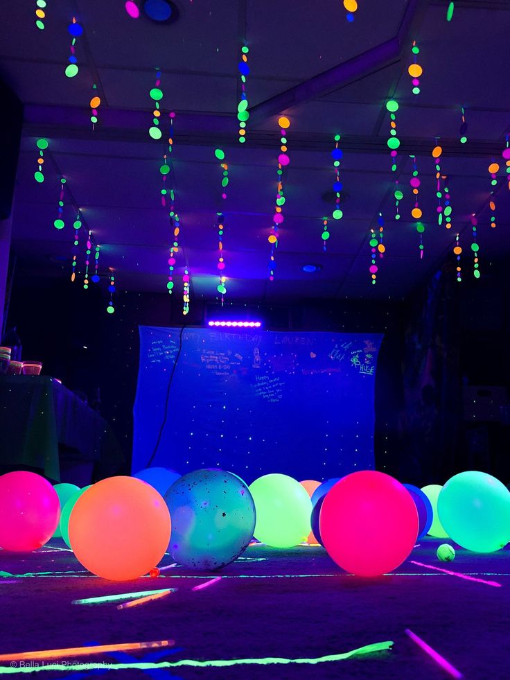 colorful balloons are lit up on the floor in front of a projector screen at night