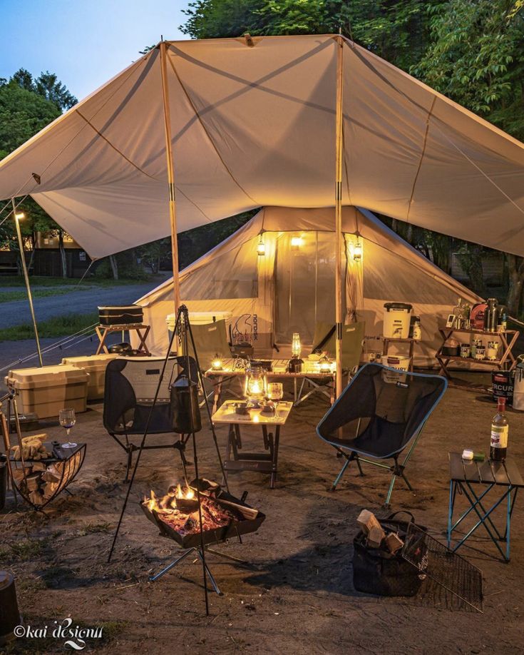 an outdoor tent set up with chairs, tables and fire pit in the foreground