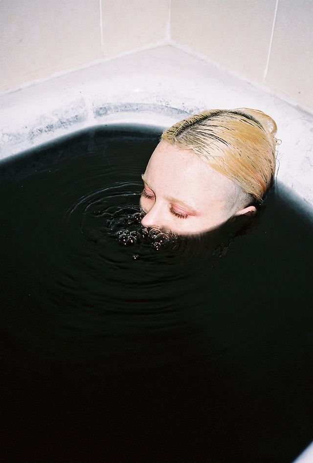 a woman with blonde hair is in the water and has her eyes closed to the side