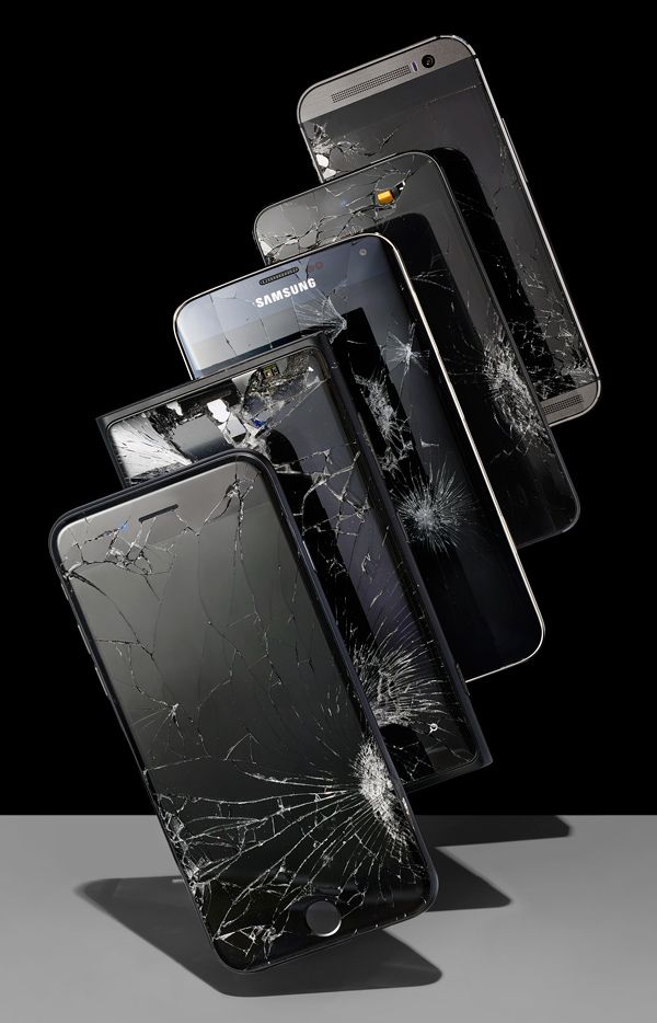 four cell phones with broken screens are shown in this image, one is black and the other is white