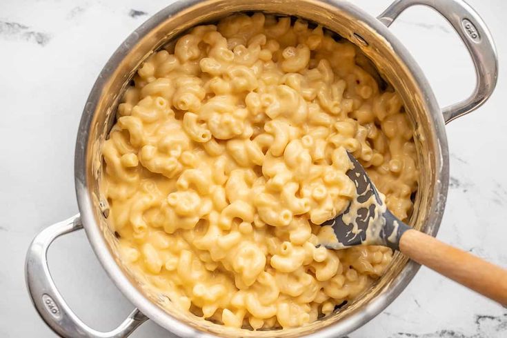 macaroni and cheese in a pot with a wooden spoon