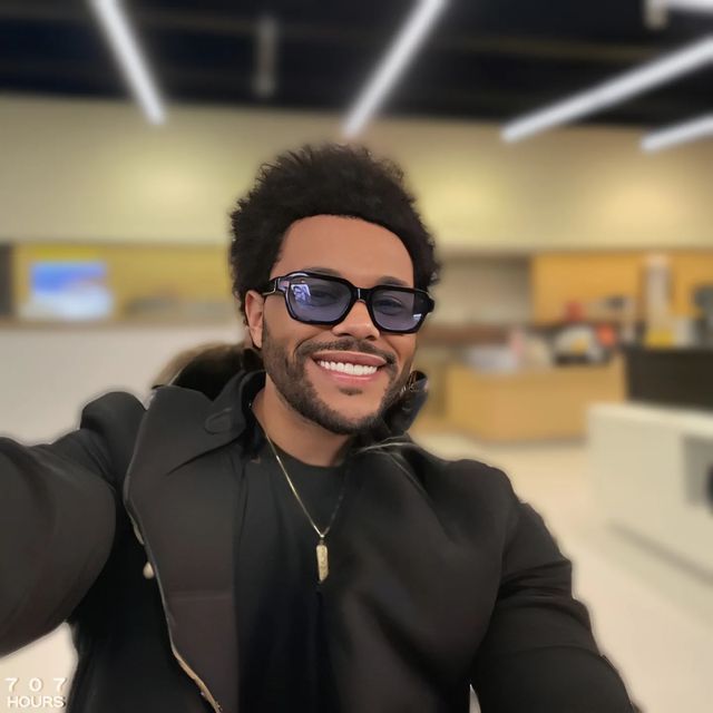 a man wearing sunglasses taking a selfie in an airport