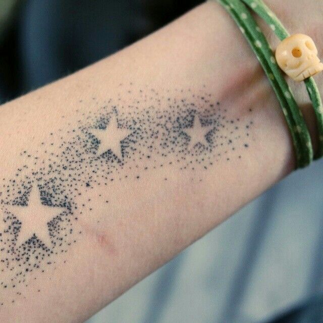 a person's arm with stars on it and a green string around the wrist