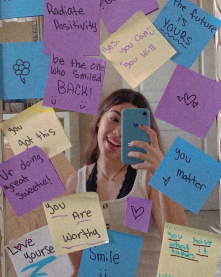 a woman taking a selfie with her cell phone surrounded by sticky notes