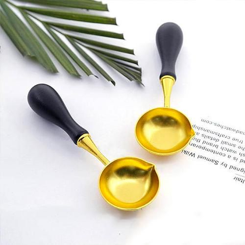 two black and gold spoons sitting next to each other on top of an open book