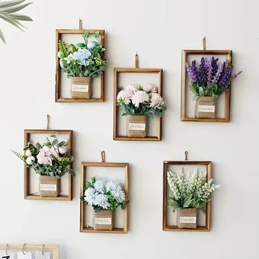 flowers are displayed in wooden frames on the wall