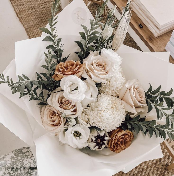 a bouquet of white and brown flowers sitting on top of a table next to an envelope