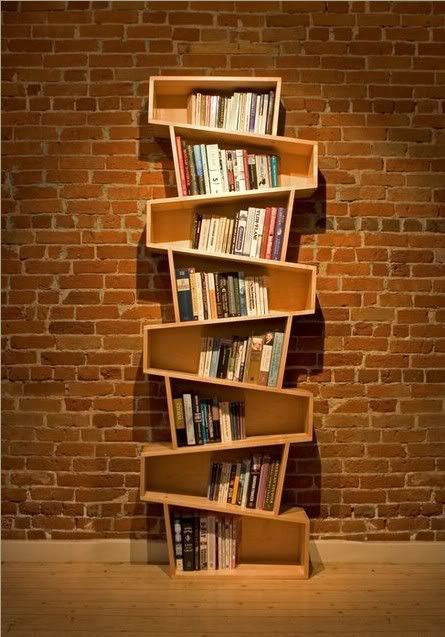 a tall wooden book shelf sitting next to a brick wall with several books on it