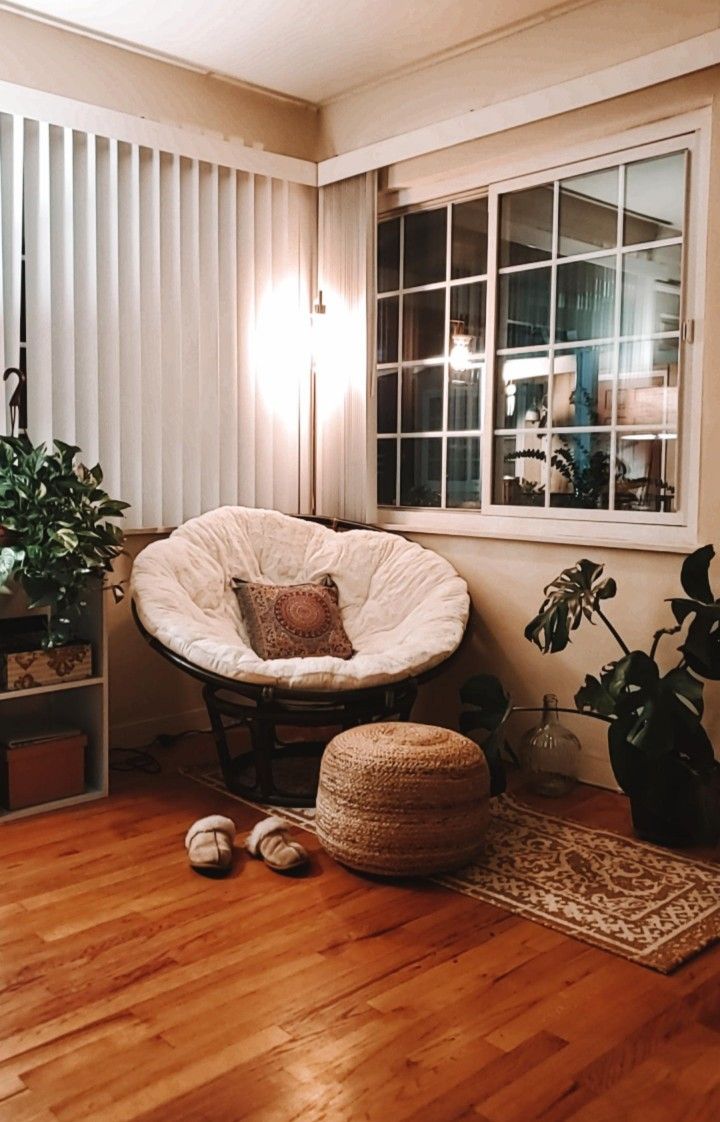 a living room filled with furniture and lots of plants on top of a hard wood floor