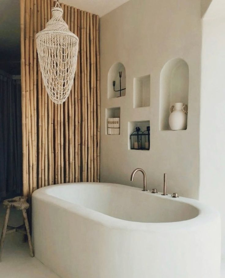 a white bath tub sitting next to a wooden wall with pictures on the walls and a chandelier hanging above it