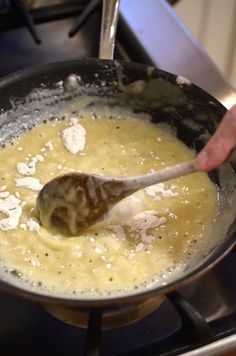 a person stirring something in a pan on the stove