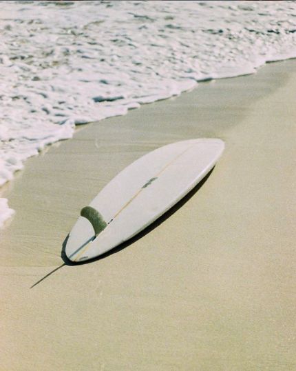 a surfboard is laying on the sand at the beach