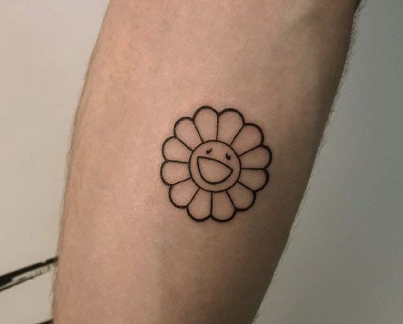 a small flower tattoo on the left forearm and arm, with a smiley face in the center