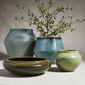 three vases with plants in them sitting on a white table top next to each other