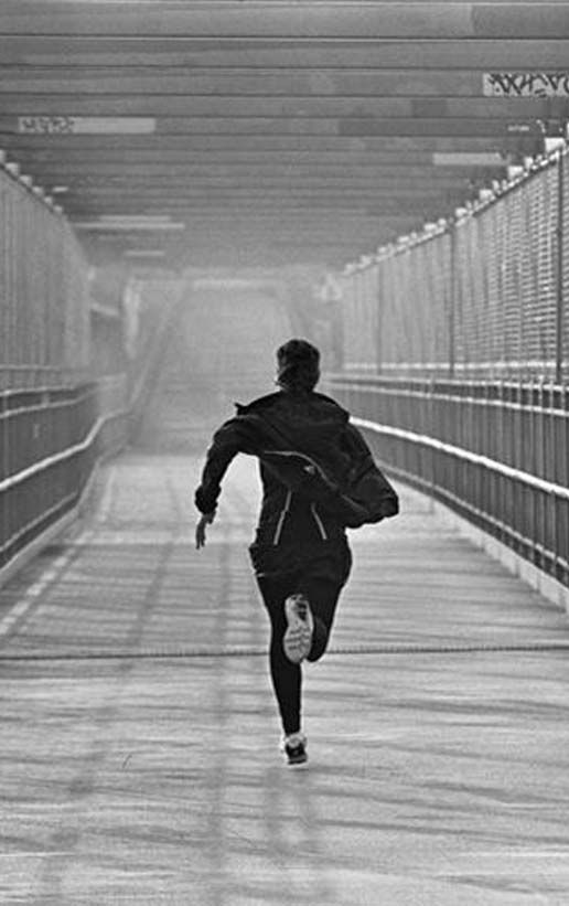 a man running across a bridge in black and white