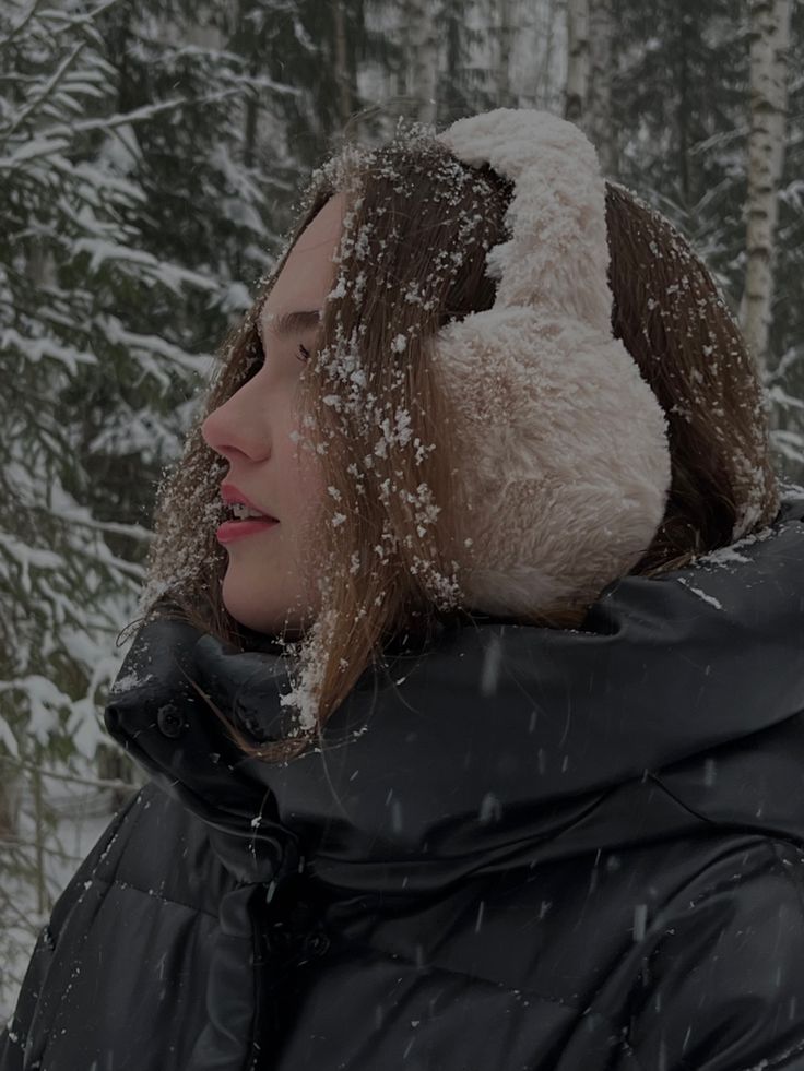 a woman standing in the snow with her head covered by a fur hat, looking off into the distance