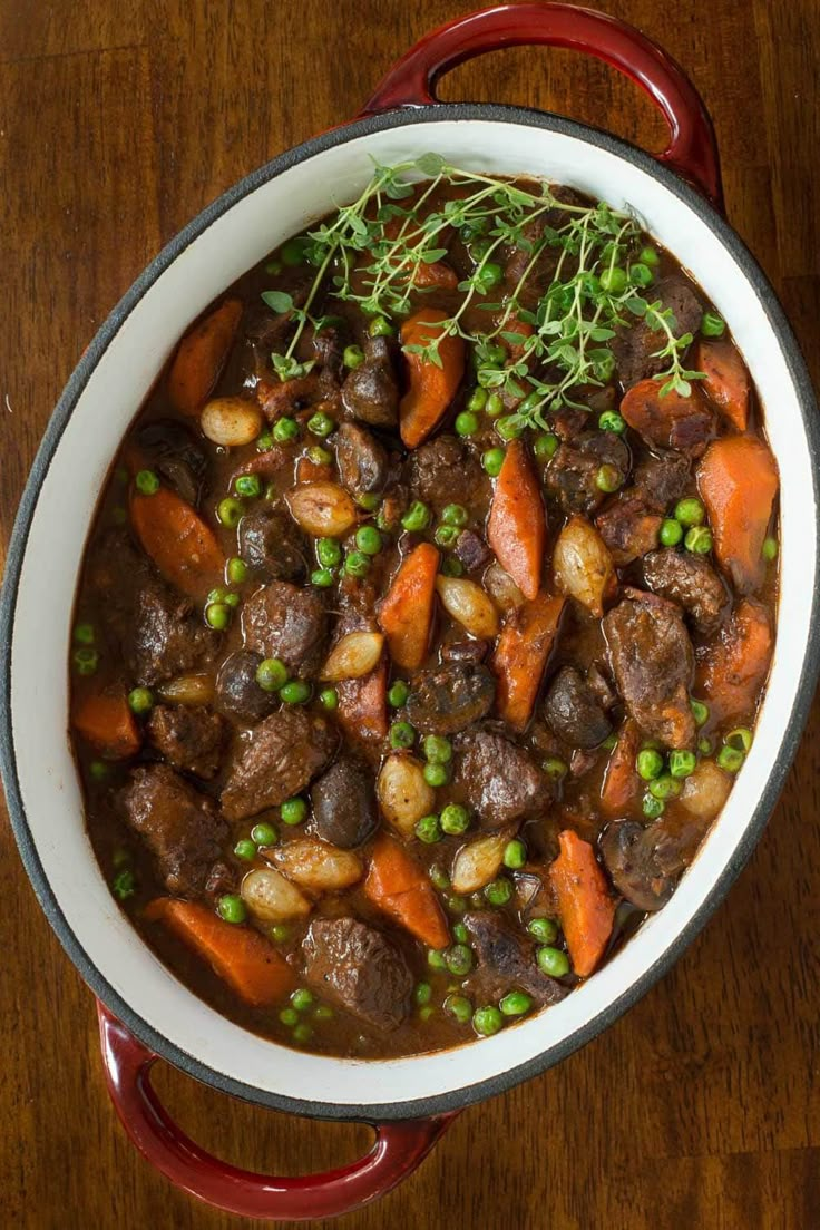 a pot filled with meat and vegetables on top of a wooden table