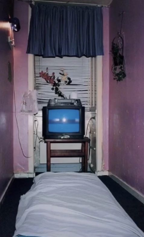 a small bed in a room with a tv on it's stand next to a window