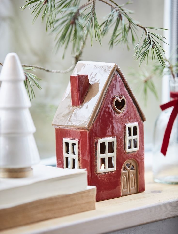 a small red house sitting on top of a table next to a christmas ornament