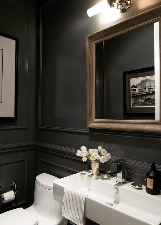 a white toilet sitting next to a sink in a bathroom under a framed mirror with flowers on it