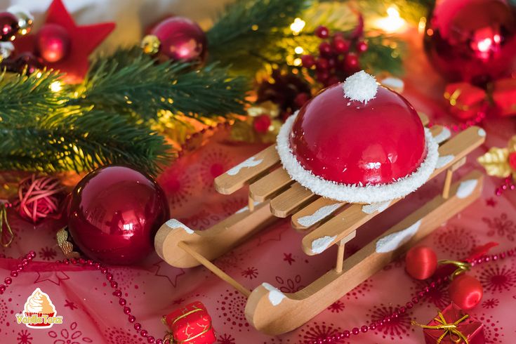 a wooden sleigh with a santa claus hat on it and christmas decorations in the background