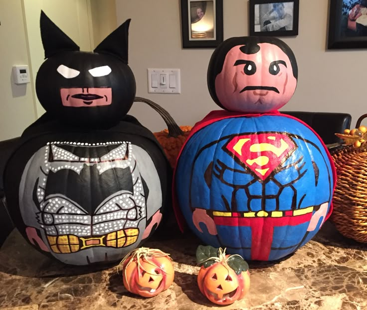 three pumpkins decorated to look like batman and superman