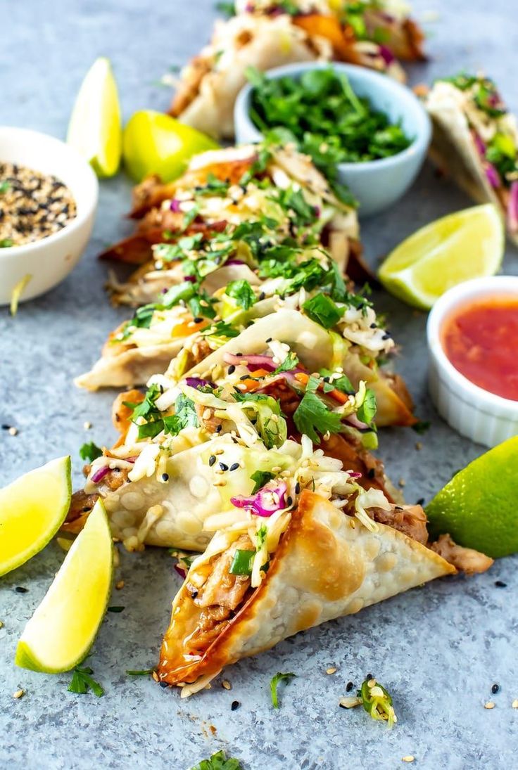 some food is laying out on the table with dipping sauces and lime wedges