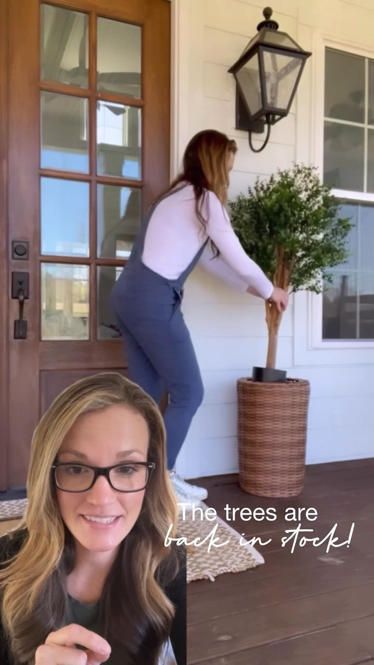 a woman is standing on the front porch with her hands in her pockets and holding a potted plant