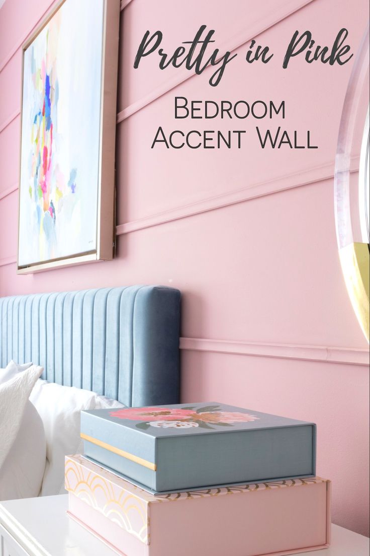 the bedroom accent wall is painted pink and has books stacked on top of each other