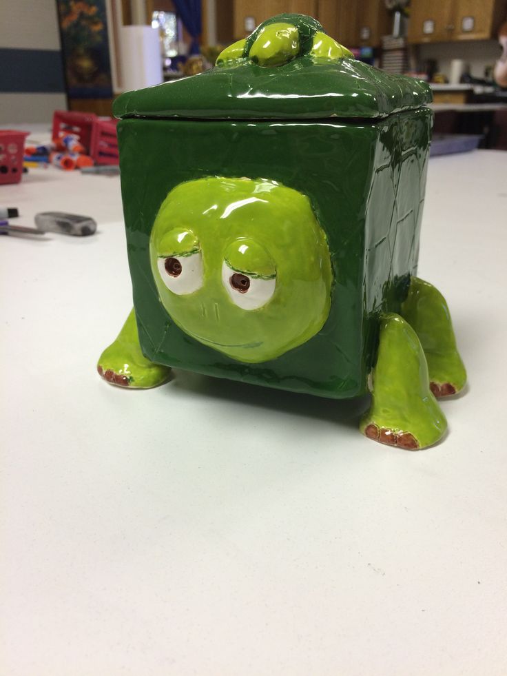 a green box with eyes and legs sitting on top of a table