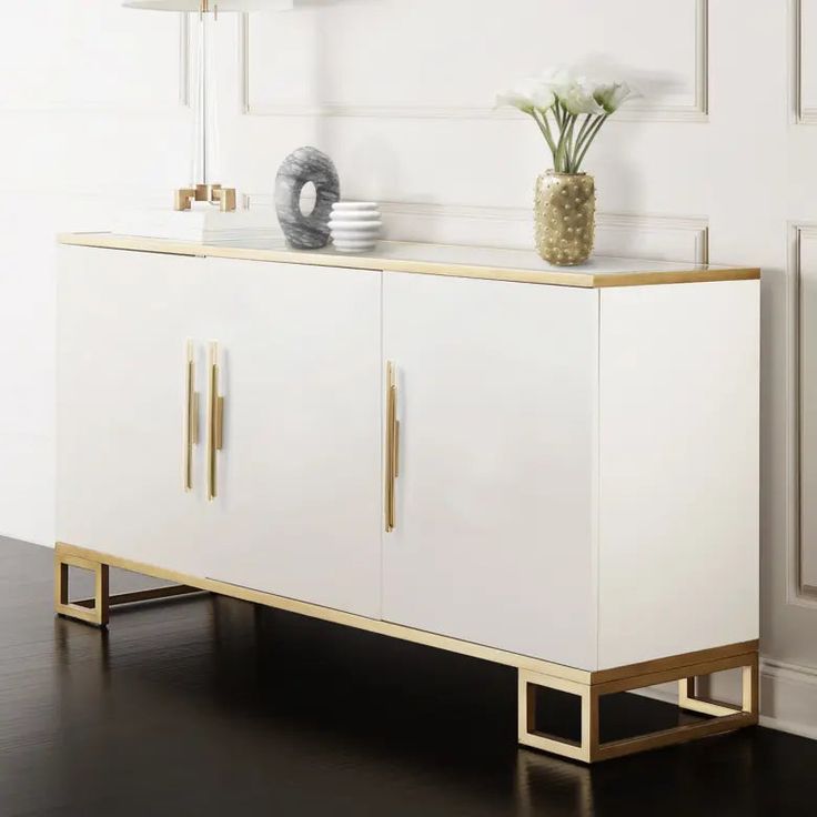 a white and gold sideboard with two vases sitting on it's sides