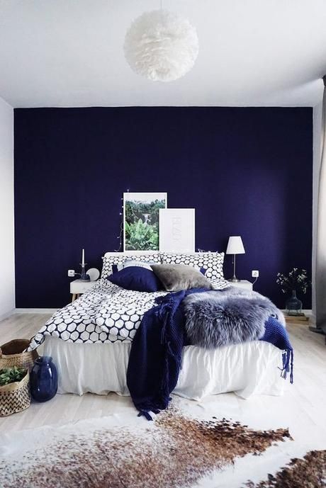 a bed room with a neatly made bed and purple walls