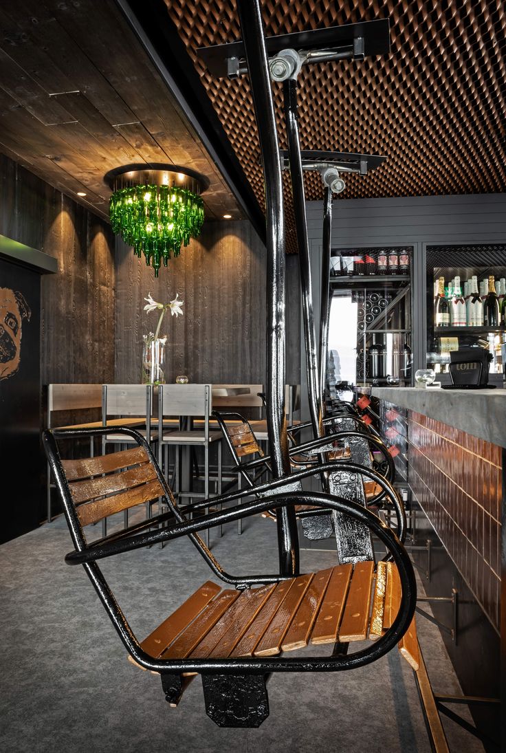 a wooden bench sitting next to a bar under a green chandelier in a restaurant