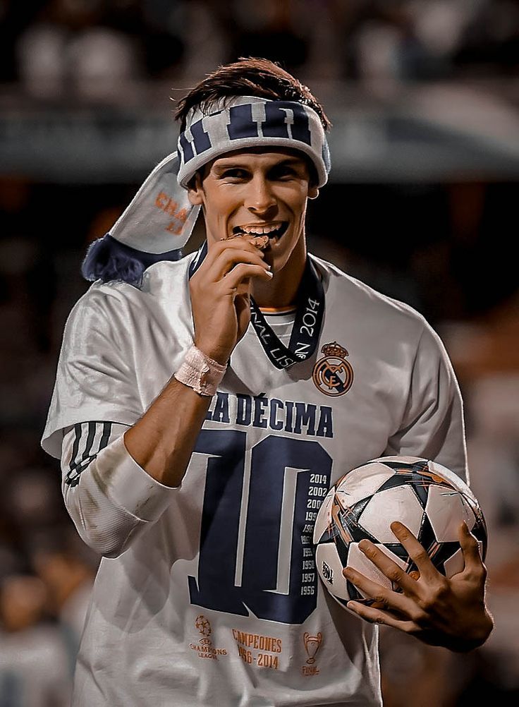 a man holding a soccer ball while wearing a head band on top of his head