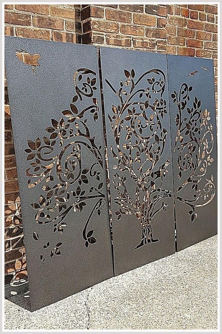 three metal panels with designs on them sitting in front of a brick wall next to a sidewalk