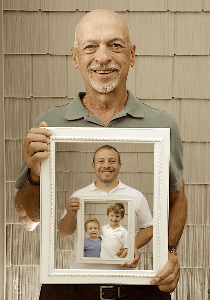 a man holding up a white frame with a photo of two children in it and an adult