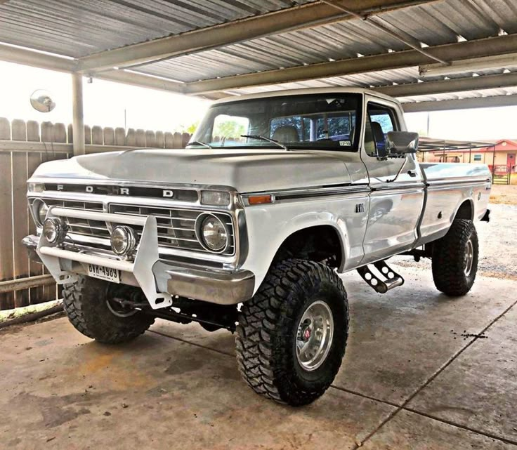 a white truck parked in a garage next to a wooden fence and metal roofing