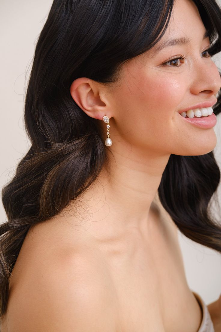 a woman in a strapless dress smiling at the camera with her hair pulled back