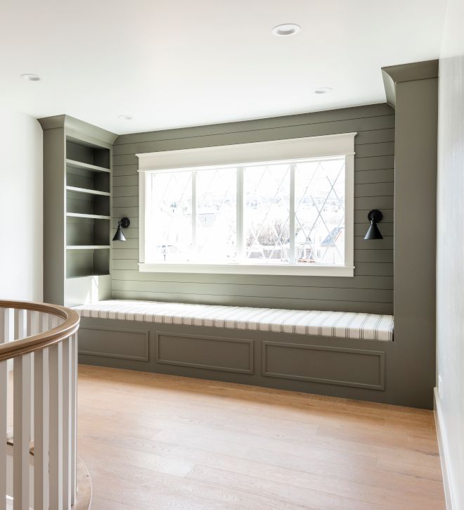 an empty room with a window and bench in the corner, next to a spiral staircase