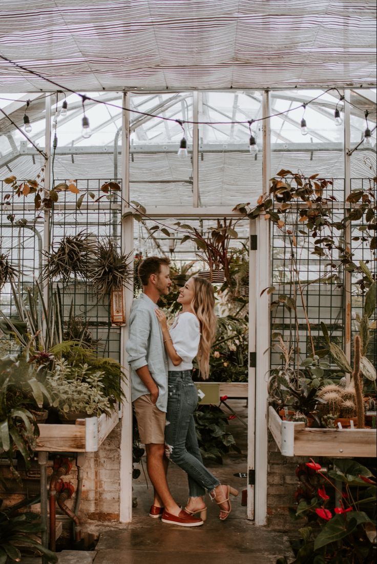 a man and woman standing next to each other in a greenhouse