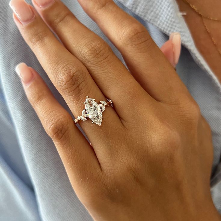 a woman's hand with a diamond ring on her left hand and the other hand holding an engagement ring