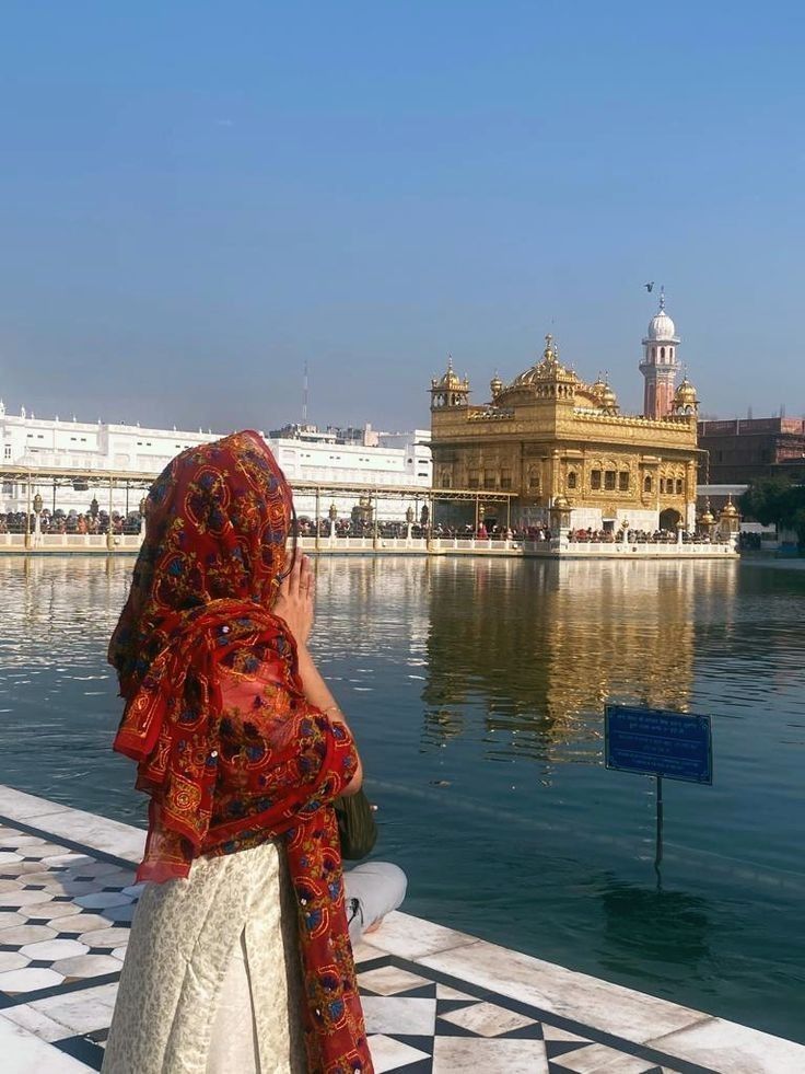 a woman standing on the edge of a body of water while looking at something in the distance