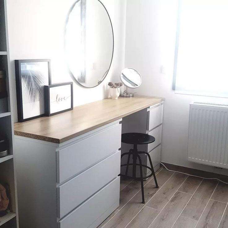 a desk with two drawers and a mirror on it in a room next to a window