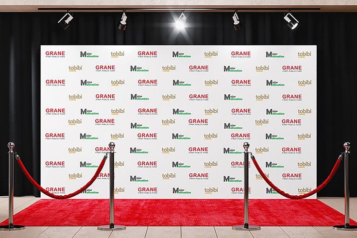 a red carpeted area with two barriers and a white wall behind it that has the name orange on it